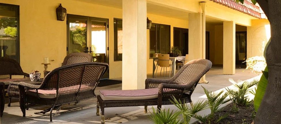 A cozy patio featuring wicker furniture and a sun lounger, perfect for relaxation.