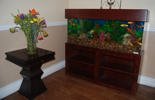 A cozy corner featuring an aquarium with colorful fish and a vase of flowers on a wooden table.