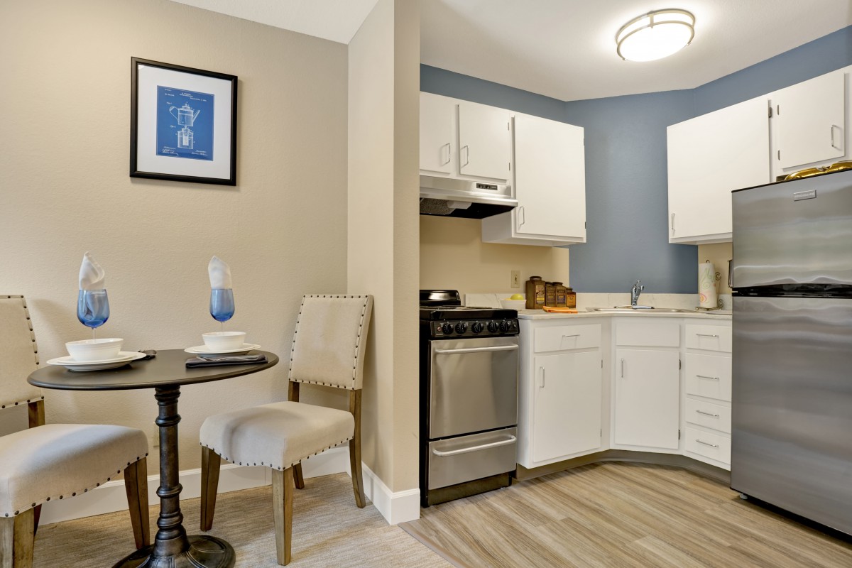 A compact modern kitchen with white cabinets and a small dining area.