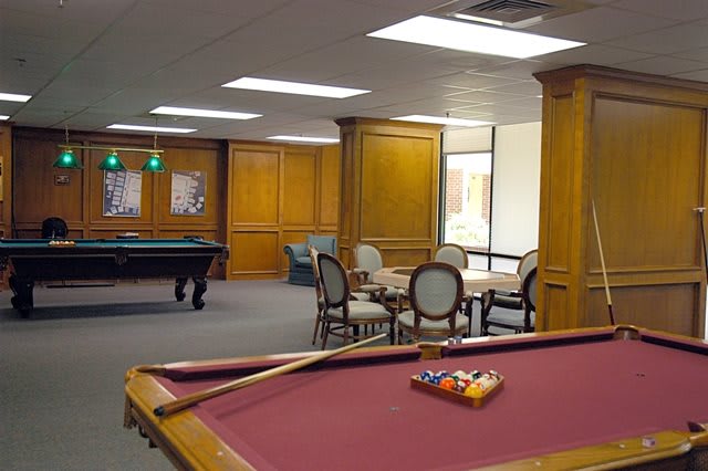 A spacious game room featuring multiple pool tables and seating areas.