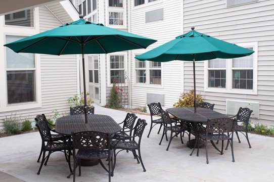 A patio with tables and chairs under green umbrellas.