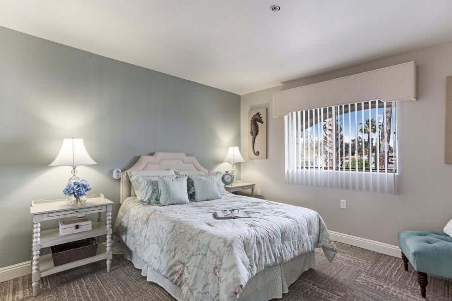 A cozy bedroom with a double bed, nightstands, and bedside lamps, featuring soft lighting and neutral tones.