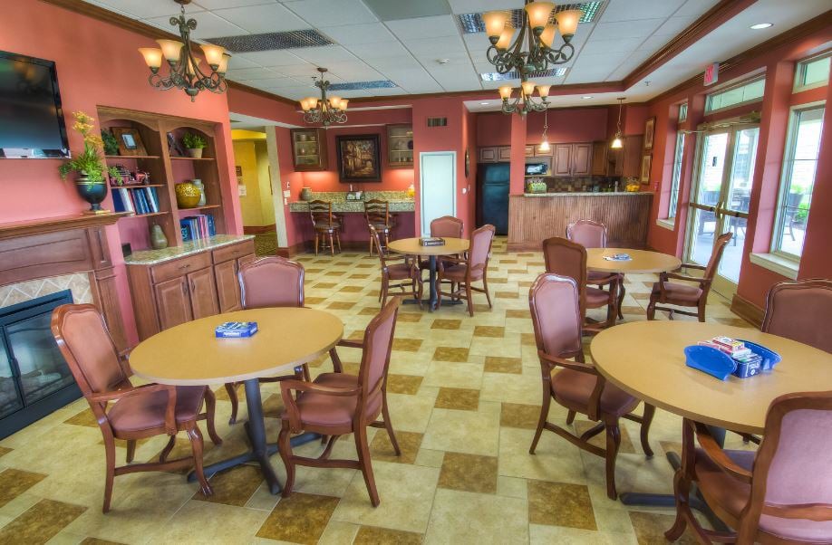 A spacious dining area with multiple tables and chairs, featuring elegant chandeliers and warm decor.