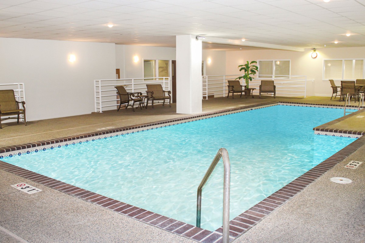 An inviting indoor swimming pool area with seating and bright lighting.