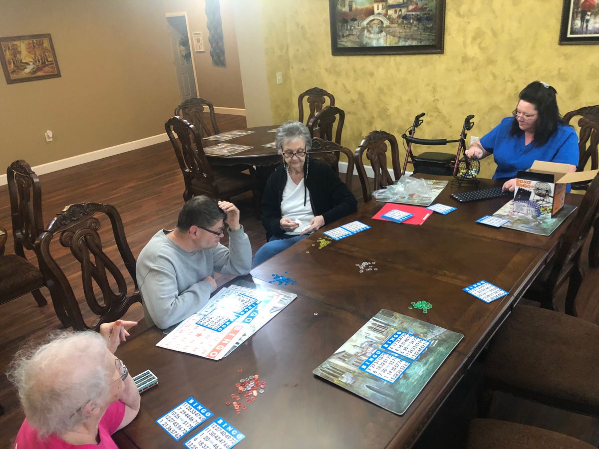 A group of seniors playing bingo around a large table indoors.