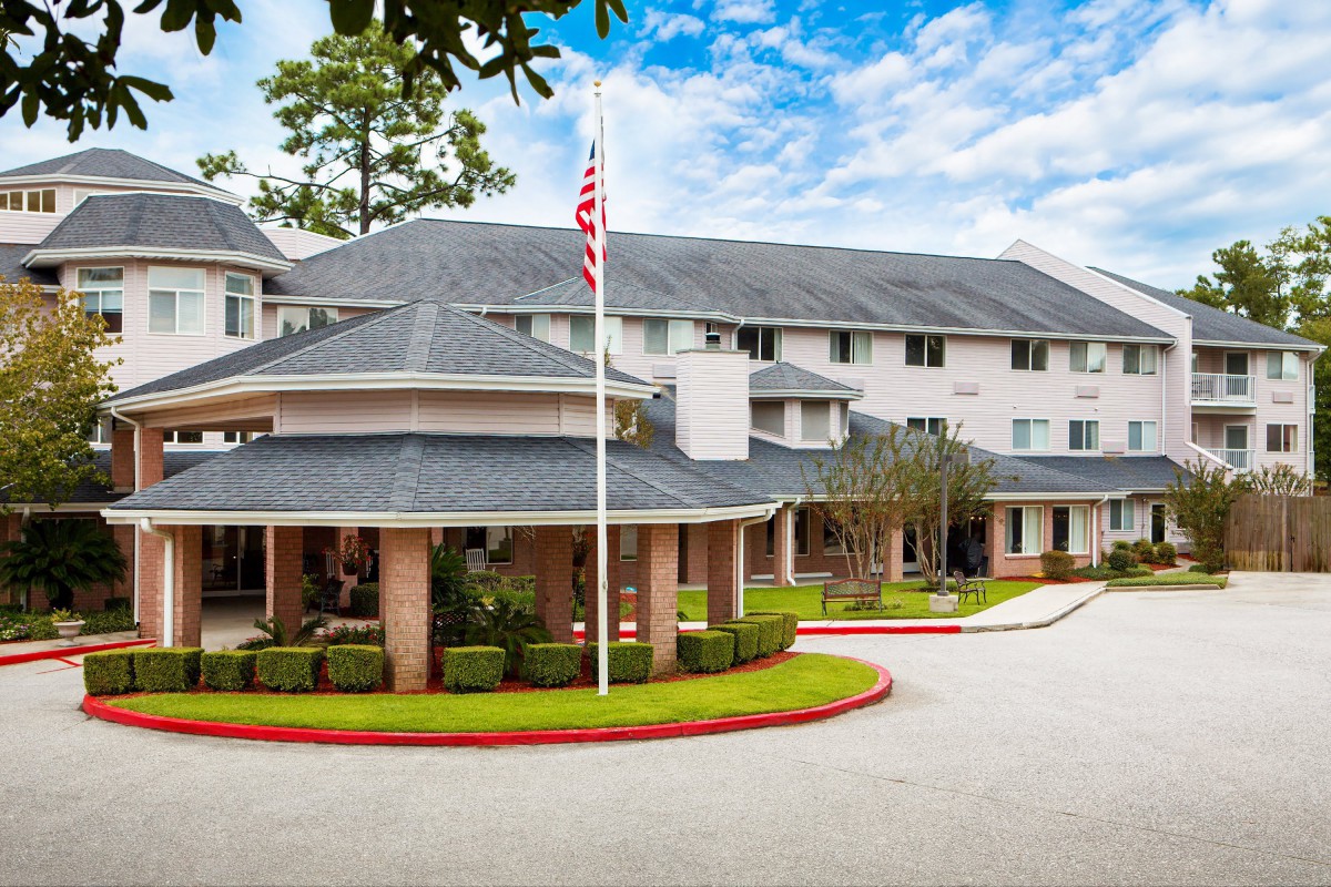 A residential building with a circular driveway and an American flag out front.