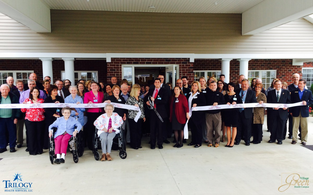 A group of people participating in a ribbon-cutting ceremony outdoors.
