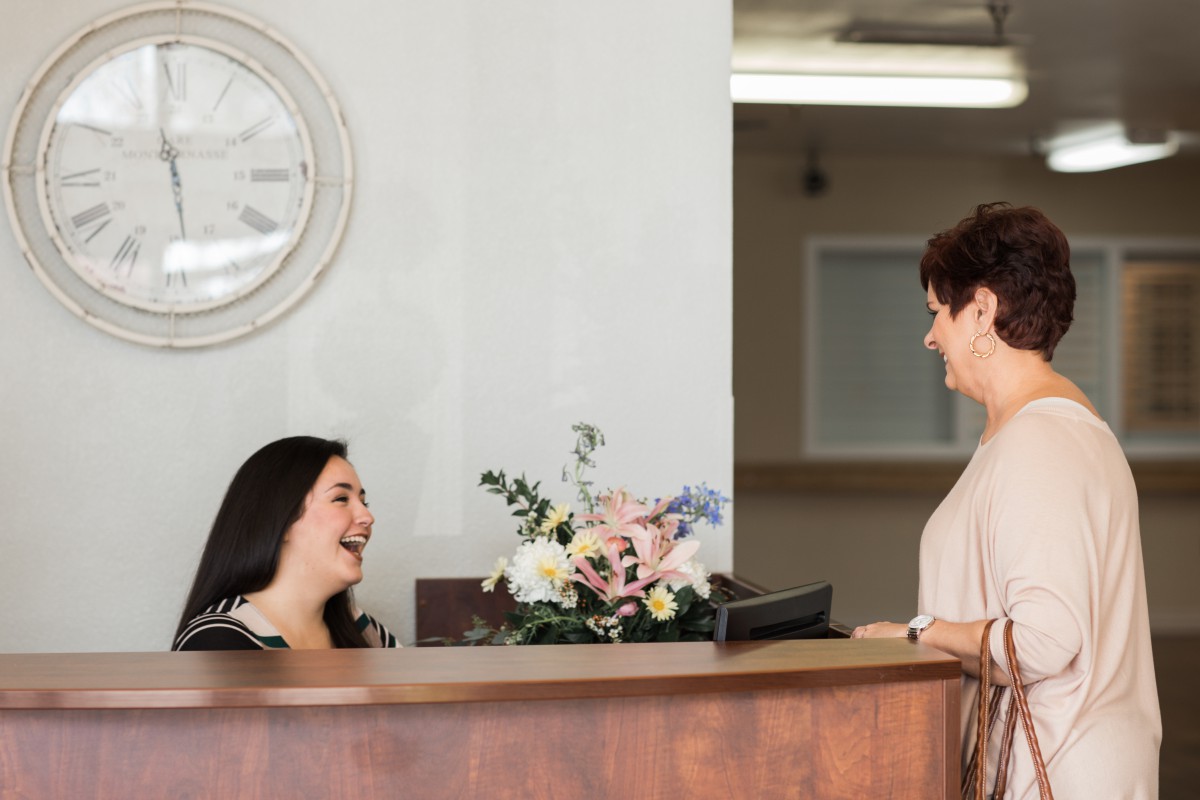 Two people having a friendly conversation at a reception desk.