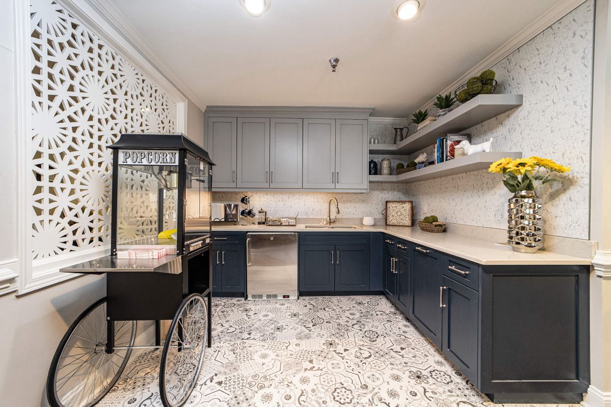 A modern kitchen featuring blue cabinets, patterned flooring, and open shelves with decorative items.