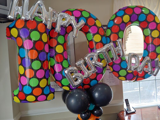 A festive setup celebrating a 100th birthday with vibrant balloons and cheerful decorations.