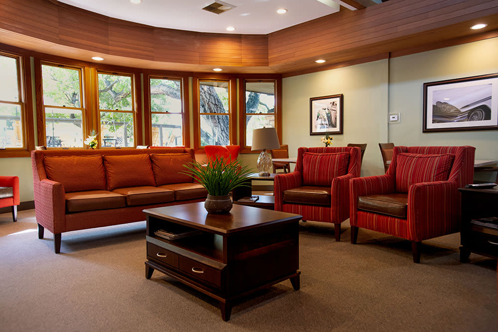 A cozy living room with comfortable seating, a central coffee table, and natural light streaming through large windows.