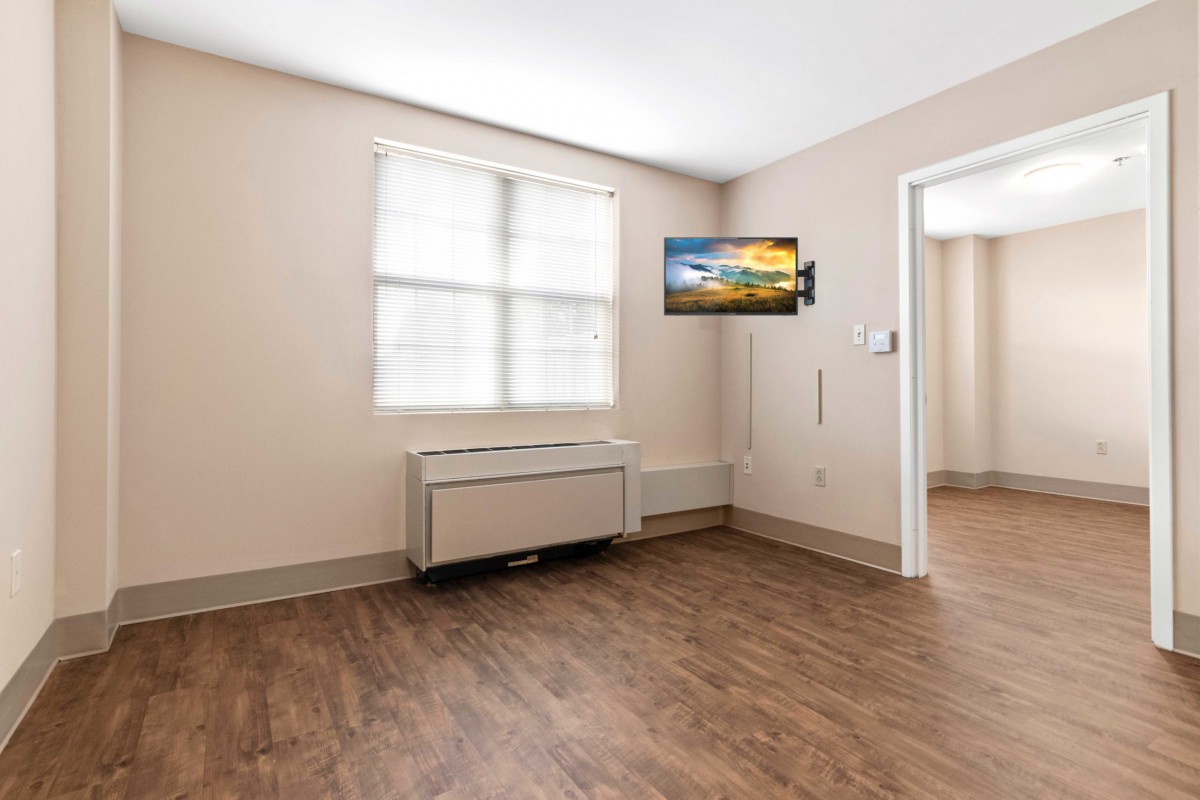 A minimalist room with a mounted TV and wooden flooring.