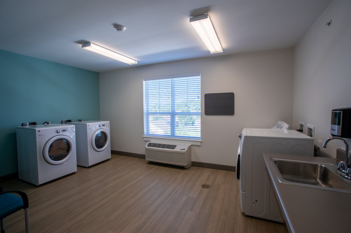 A clean and organized laundry room featuring washing machines, dryers, and ample natural light.
