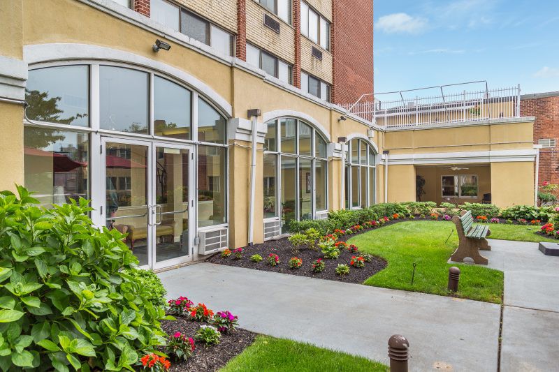 A beautifully landscaped garden area outside a modern building with large arched windows.