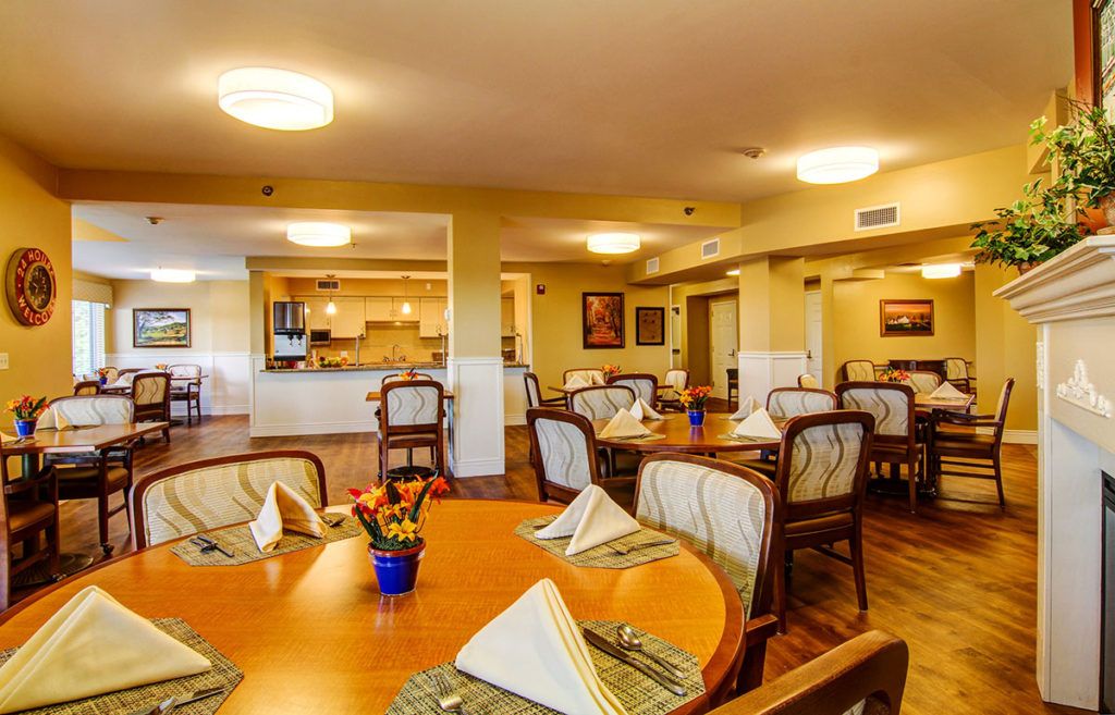 A warmly lit dining area with neatly set tables and chairs, ready for guests.