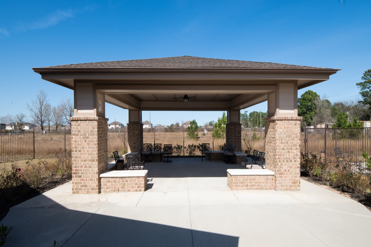A brick gazebo with seating under a clear blue sky.