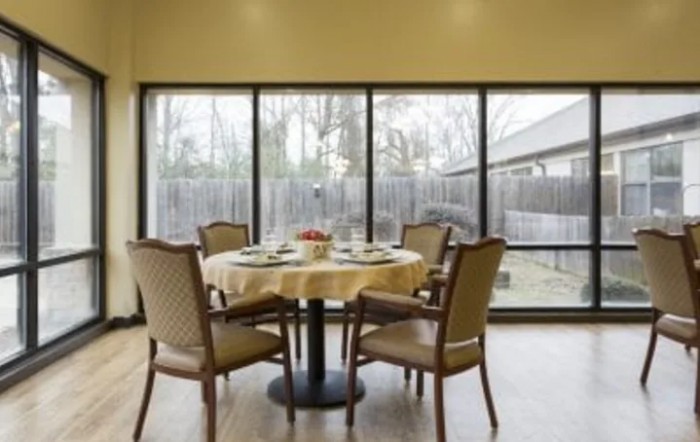 A cozy dining room with a round table and four chairs, surrounded by large windows providing natural light.