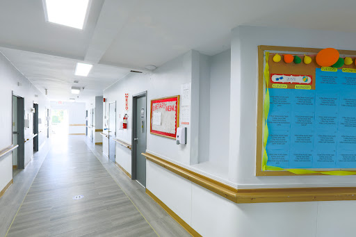 A well-lit hospital corridor showcasing the interior design with doors and a bulletin board.