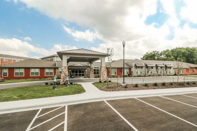 A modern building with a spacious parking lot and a partly cloudy sky overhead.