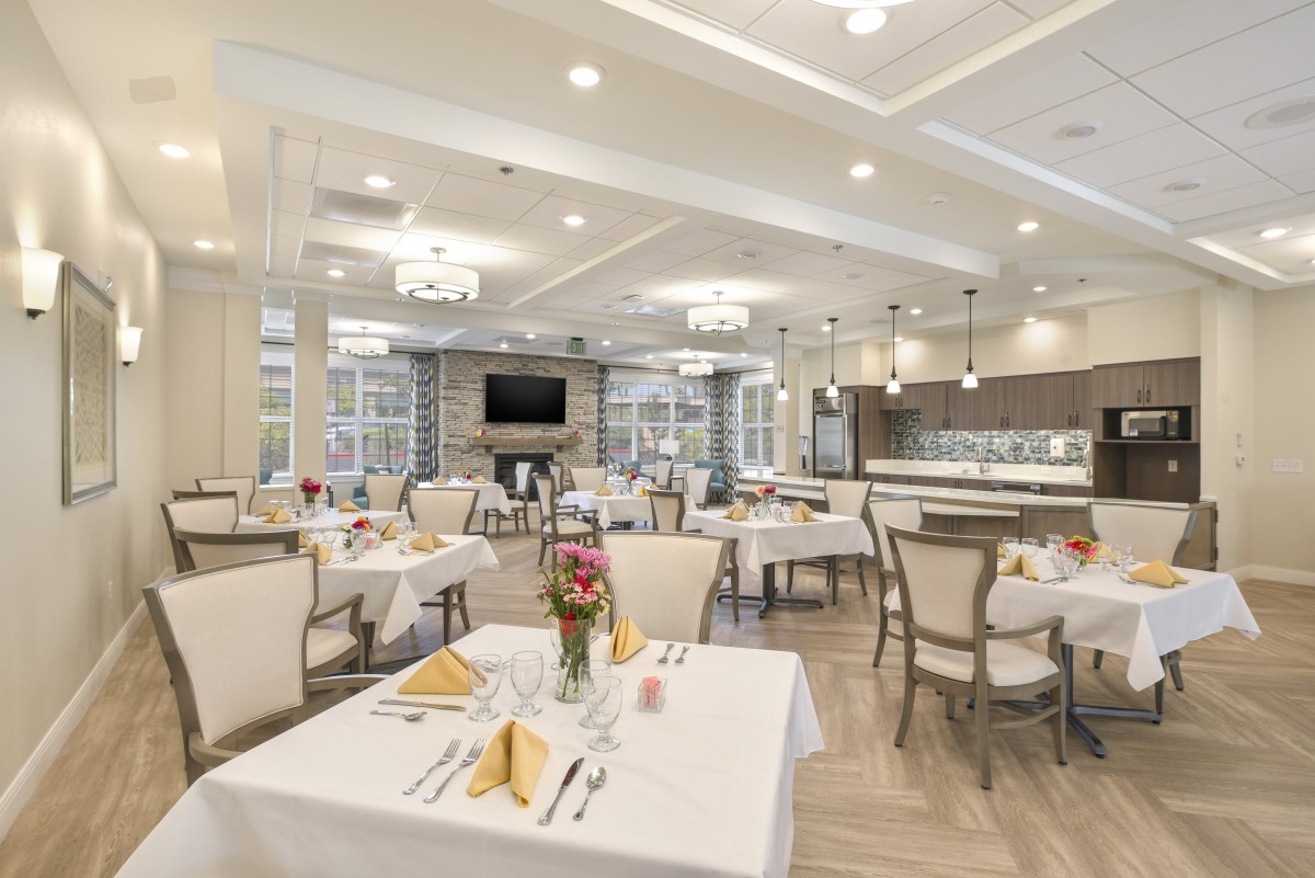 An elegant dining room with neatly arranged tables and chairs, featuring chandeliers and modern decor.