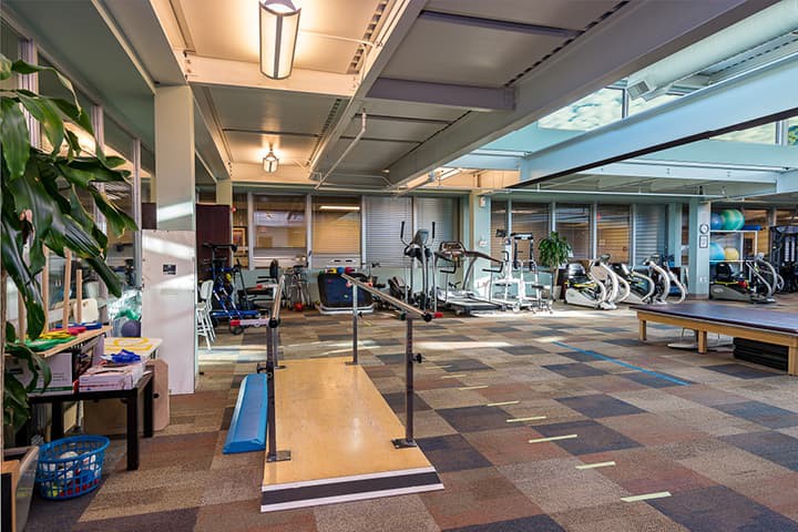 A modern gym with various exercise equipment and a well-lit workout area.