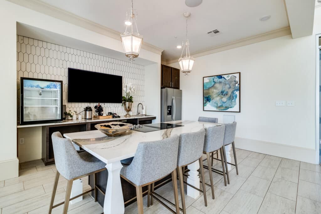 A modern dining area with a marble countertop and bar stools, featuring minimalist decor and pendant lighting.