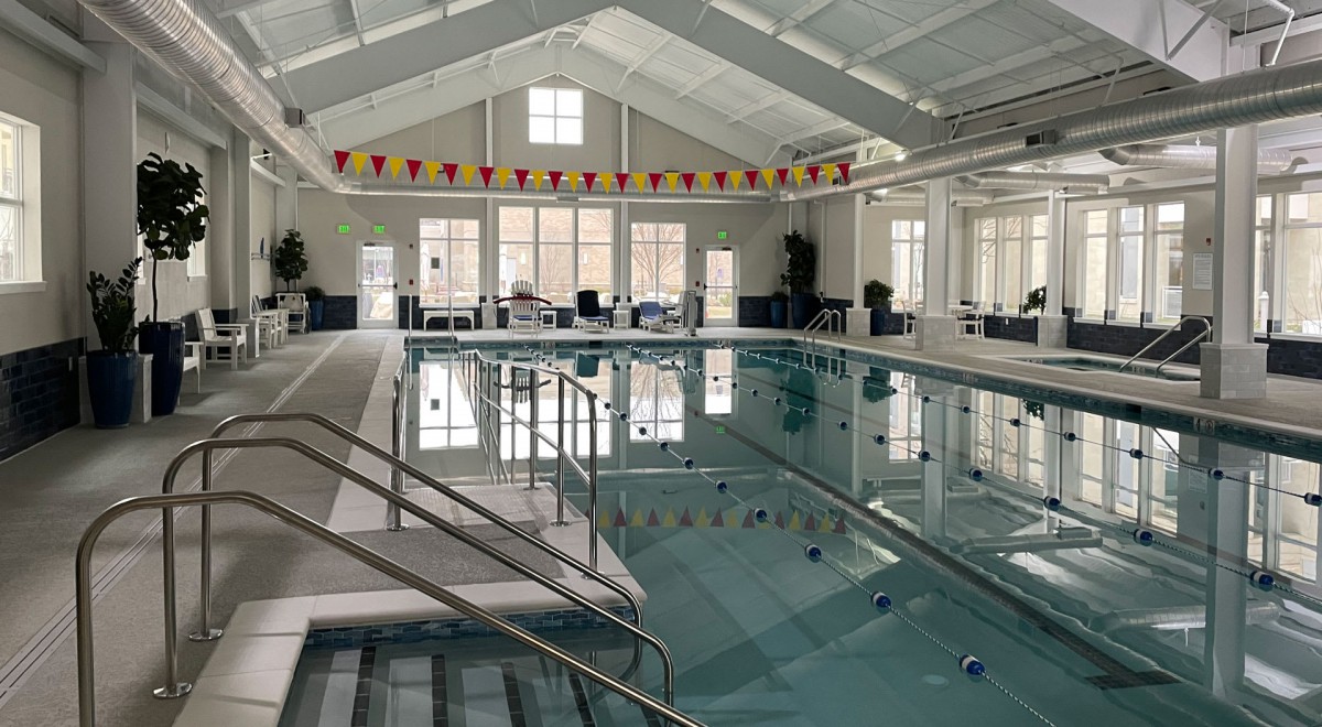 A spacious indoor swimming pool with ample natural light and seating area.