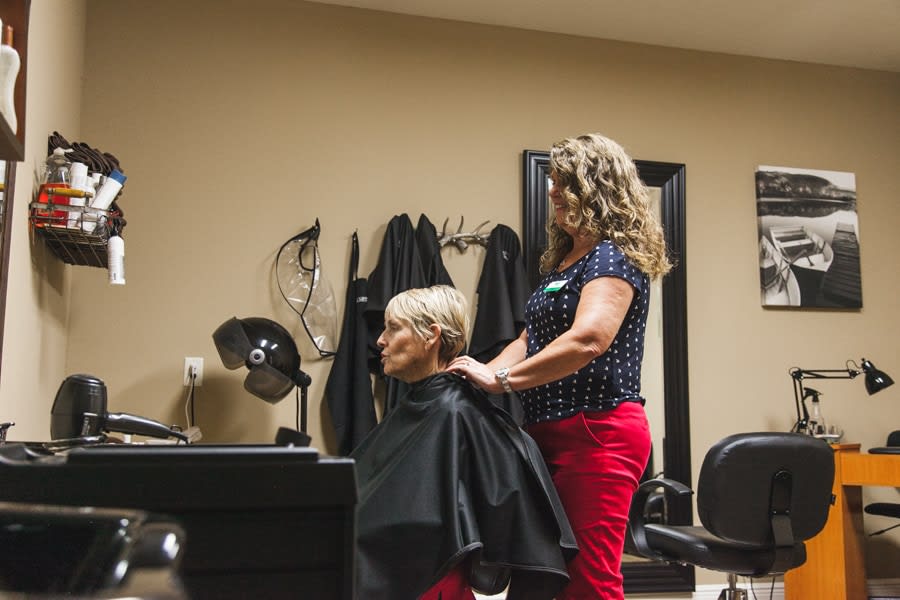 A hairstylist working on a client's hair inside a salon.