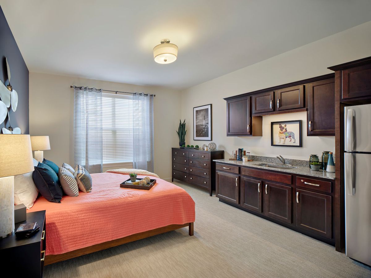A cozy bedroom with a bed, cabinets, and natural light from a window.
