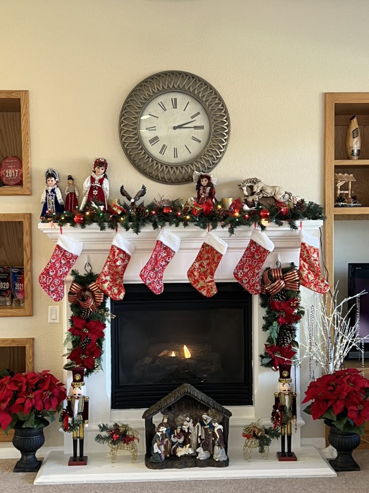 A cozy fireplace decorated for Christmas with stockings, garlands, and poinsettias.