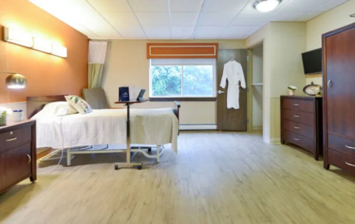 A clean and modern hospital room featuring a single bed, a window, and medical equipment.