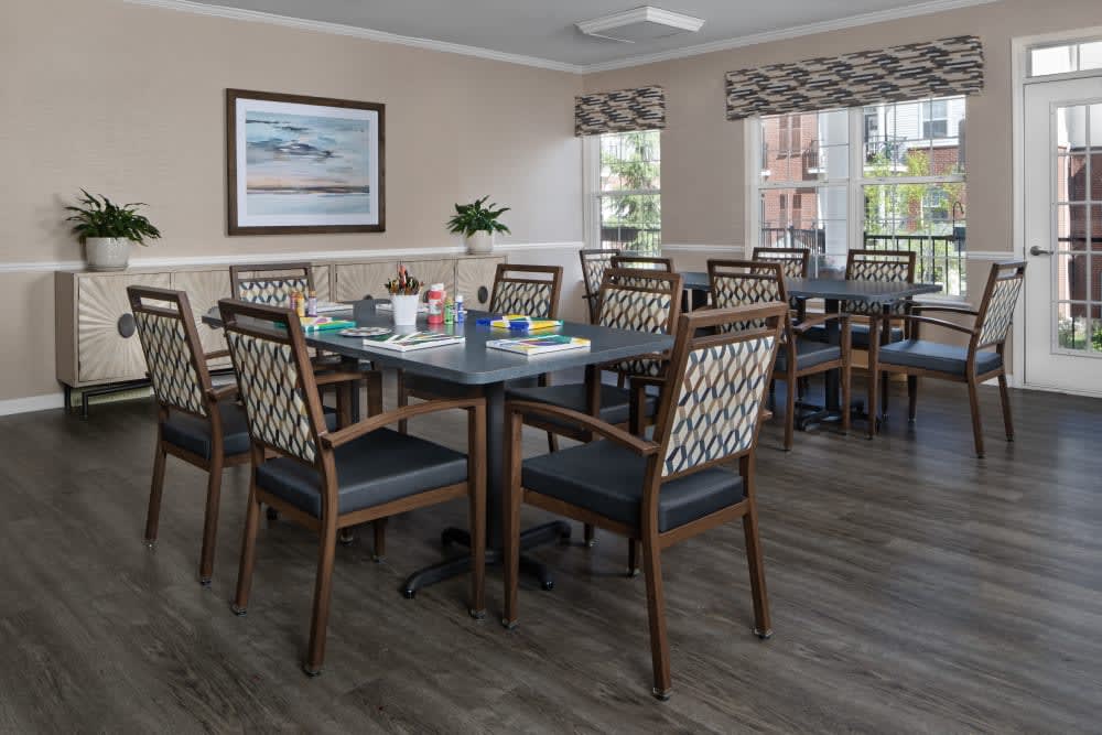A well-lit dining room with neatly arranged tables and chairs, featuring large windows and tasteful decor.