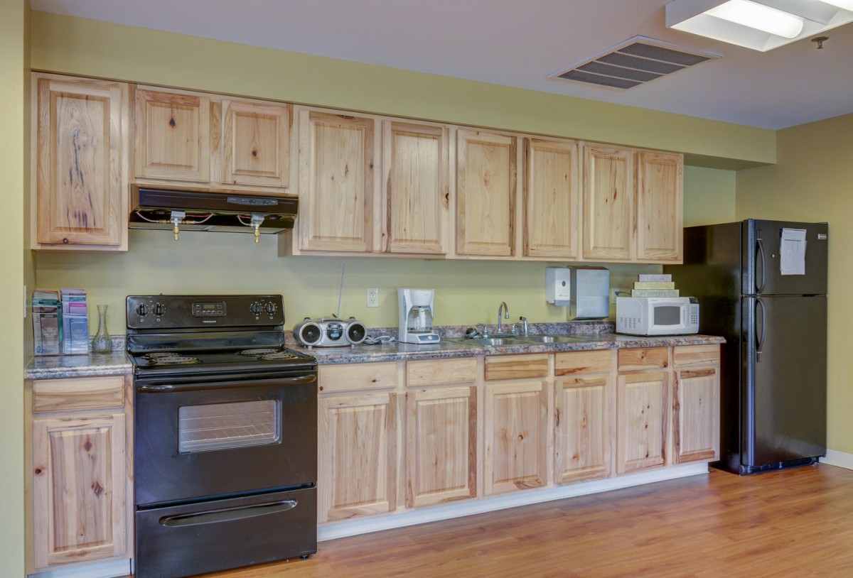 A kitchen featuring wooden cabinets and a variety of appliances, including a stove and microwave.