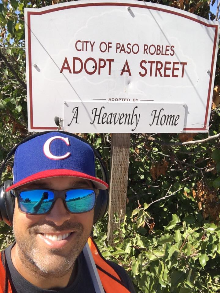Person taking a selfie in front of an 'Adopt a Street' sign in Paso Robles.