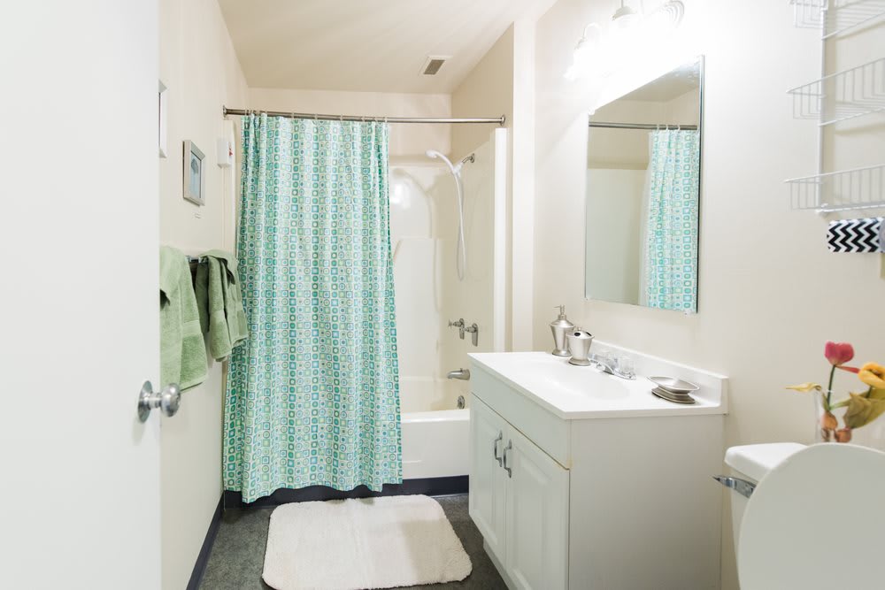 A clean and bright bathroom with a shower and mint green curtain.