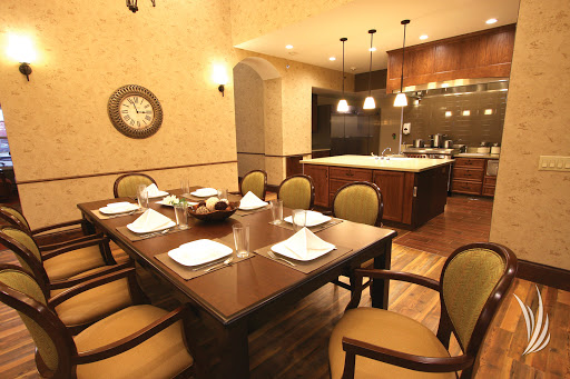 A beautifully arranged dining room featuring a wooden table set for a meal, surrounded by elegant chairs and modern kitchen aesthetics.