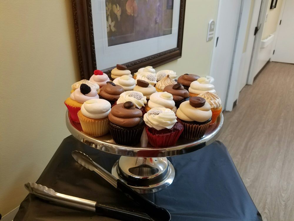 A decorative stand filled with assorted cupcakes topped with frosting and garnishes.