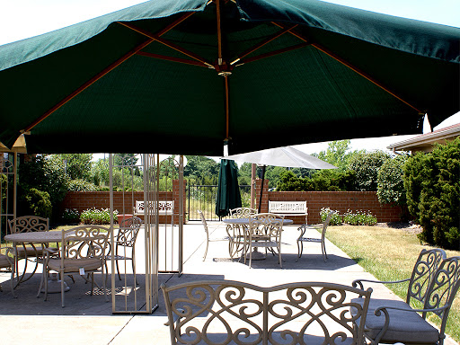 A serene outdoor patio area featuring metal furniture and a green umbrella.