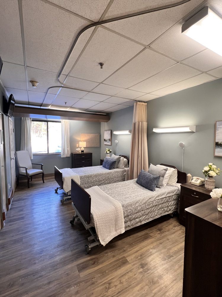 A hospital room with two neatly made beds and soft lighting.