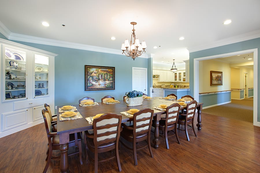 Spacious dining room with a large table, elegant chandelier, and tasteful decor.