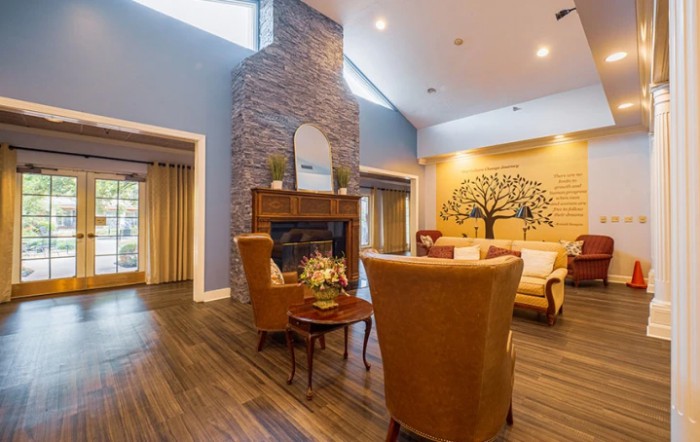 A cozy living room with a fireplace, comfortable armchairs, and decorative wall art.