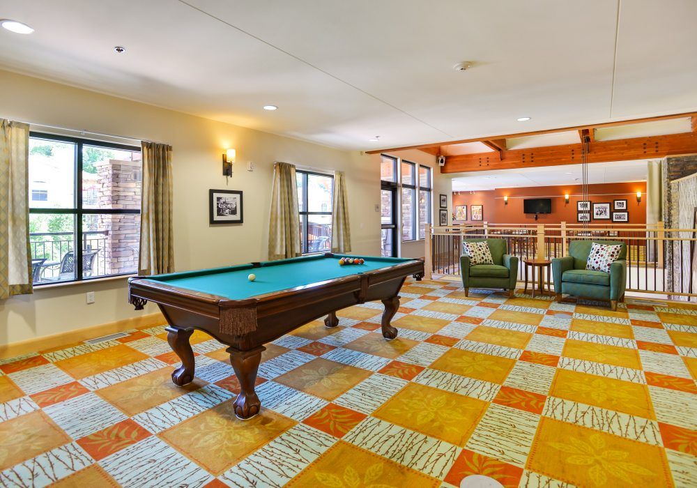 A spacious game room featuring a pool table and a comfortable seating area.
