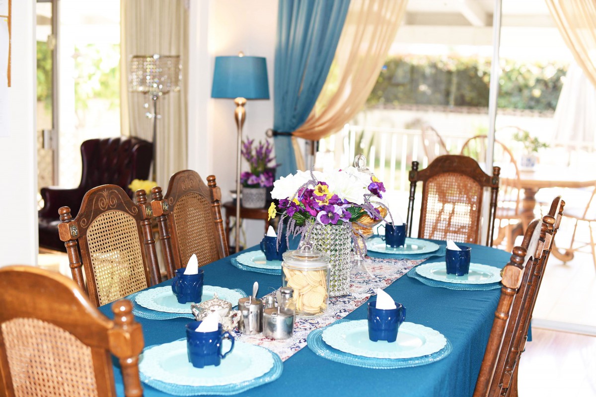 A beautifully set dining table with blue accents and floral centerpiece.