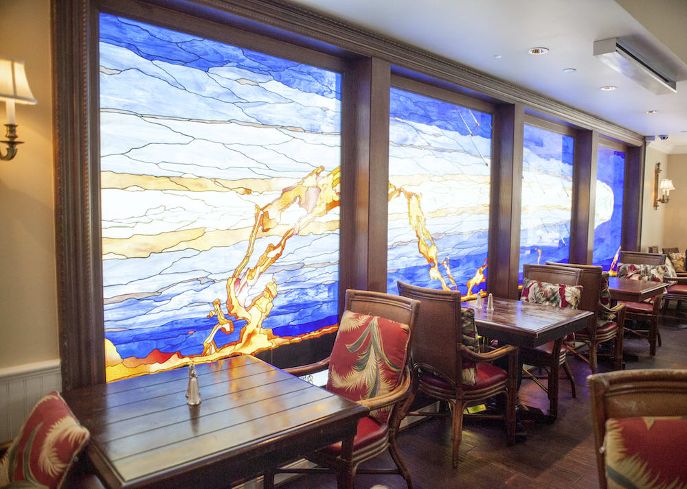 A cozy restaurant interior featuring vibrant stained glass windows and comfortable seating.