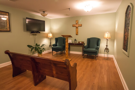 A peaceful chapel interior featuring wooden benches, a podium, and soft lighting.