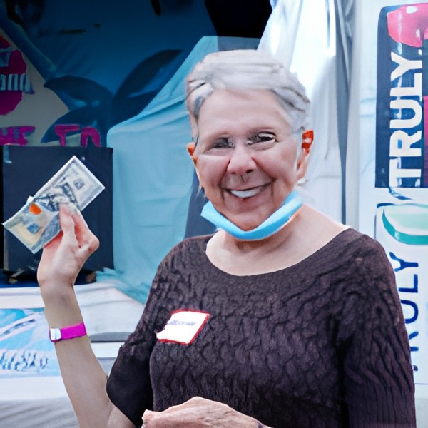 A woman is smiling while holding money at an outdoor event.