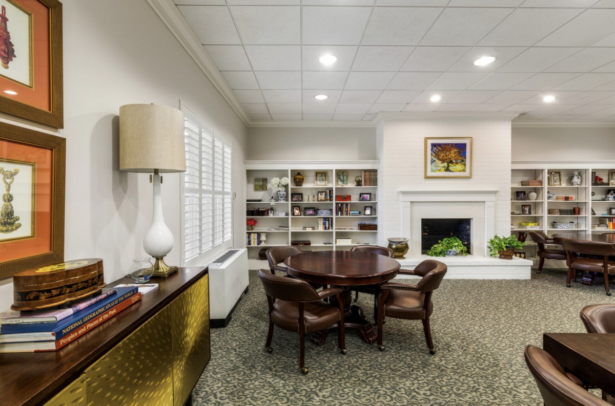 A cozy office space featuring a round table with chairs, bookshelves, and elegant decor.