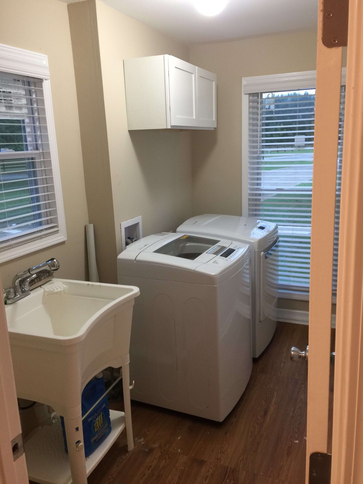 A compact laundry room with a washing machine, dryer, and utility sink.