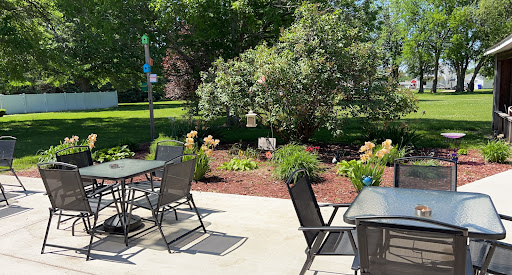 A serene outdoor patio area with seating surrounded by lush greenery and vibrant flowers.