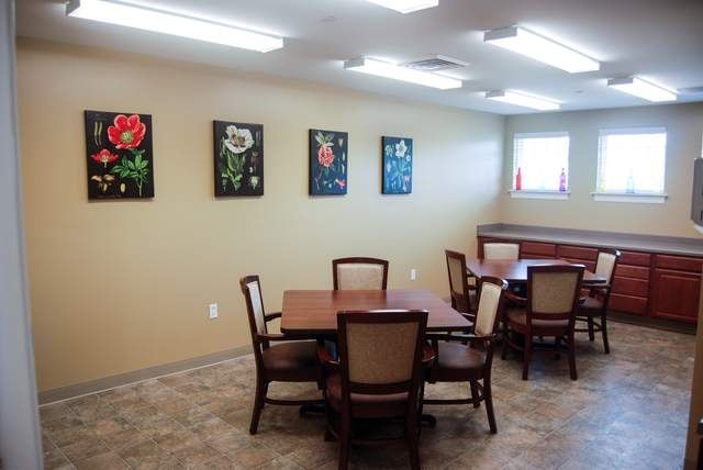 A well-lit dining area with wooden tables and chairs, adorned with floral artwork on the walls.